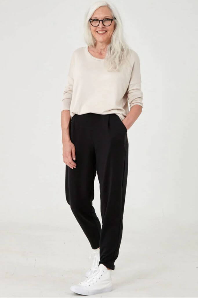 A woman wearing a white tee and black pants.