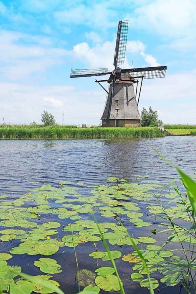 An old windmill next to a pond.